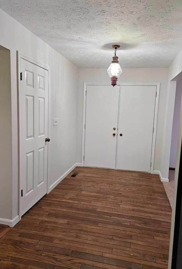 doorway with a textured ceiling and dark wood-type flooring