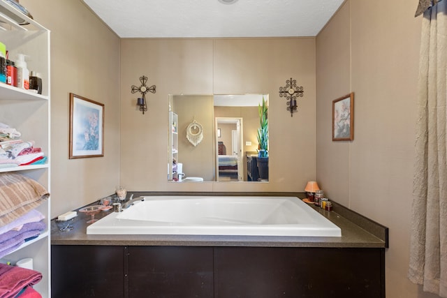 bathroom with a textured ceiling and a tub