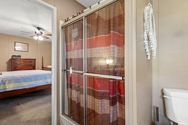 bathroom with ceiling fan, toilet, and an enclosed shower