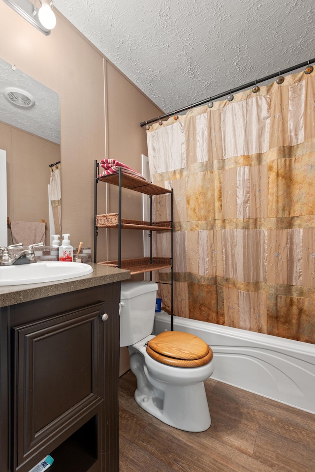 full bathroom featuring shower / tub combo, toilet, vanity, and a textured ceiling