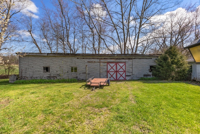 back of property featuring an outdoor structure and a yard