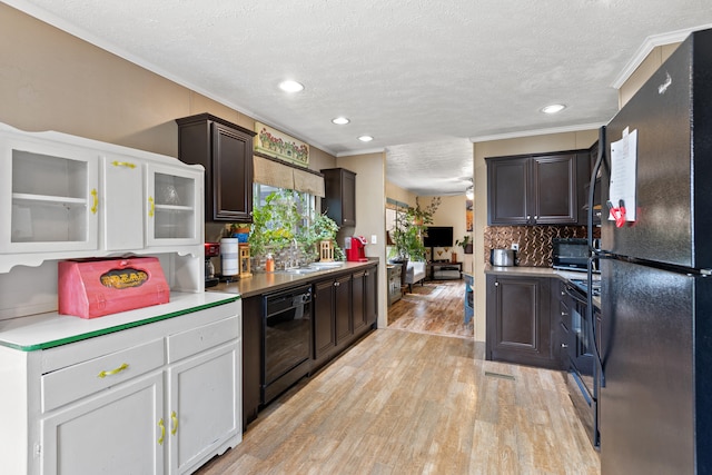 kitchen with light hardwood / wood-style floors, tasteful backsplash, black refrigerator, crown molding, and a textured ceiling