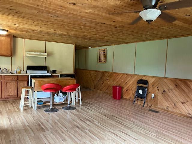 living room with ceiling fan, light wood-type flooring, sink, and wooden ceiling