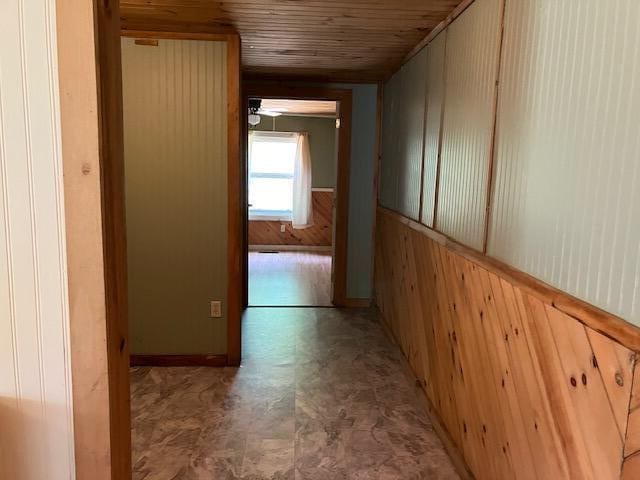 corridor with wood walls and light tile patterned floors