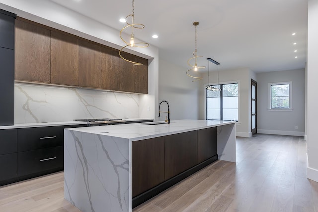 2420 Flying Ebony Dr, Lexington, KY 40509 - kitchen featuring decorative backsplash, modern cabinets, an island with sink, a sink, and light wood-style floors
