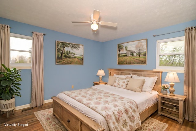 bedroom featuring a ceiling fan, baseboards, visible vents, and wood finished floors