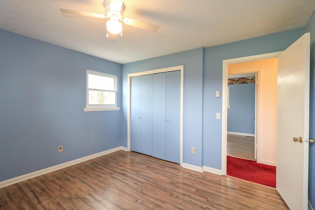 unfurnished bedroom with a closet, wood finished floors, a ceiling fan, and baseboards