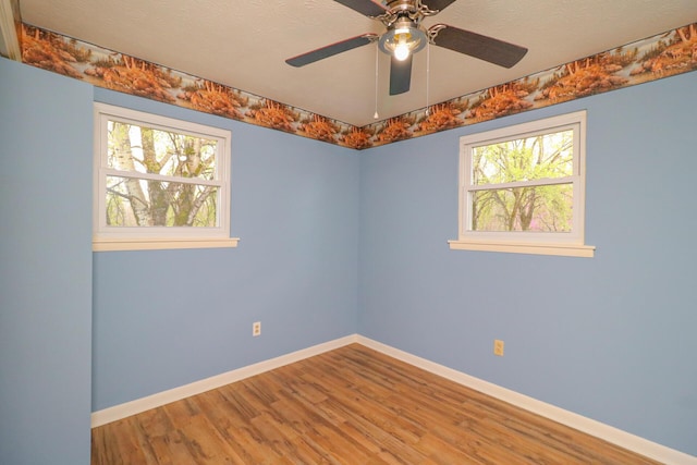 unfurnished room featuring a textured ceiling, baseboards, and wood finished floors