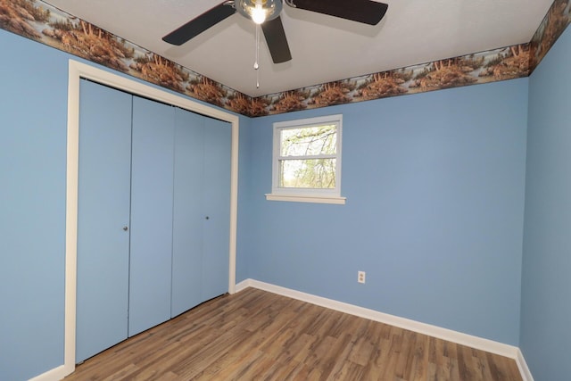 unfurnished bedroom with ceiling fan, a closet, baseboards, and wood finished floors