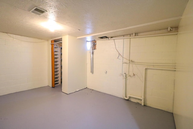 unfinished basement with a textured ceiling and visible vents