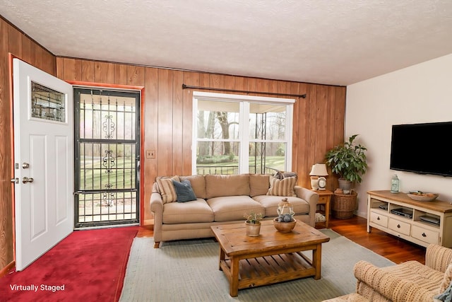 living room featuring wood walls, a textured ceiling, and wood finished floors