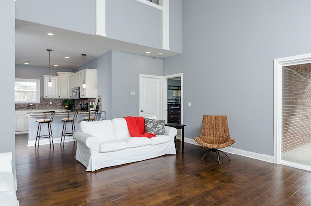 living room with dark wood-type flooring and a high ceiling