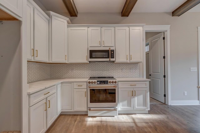 kitchen with tasteful backsplash, high end stove, white cabinetry, and light hardwood / wood-style floors