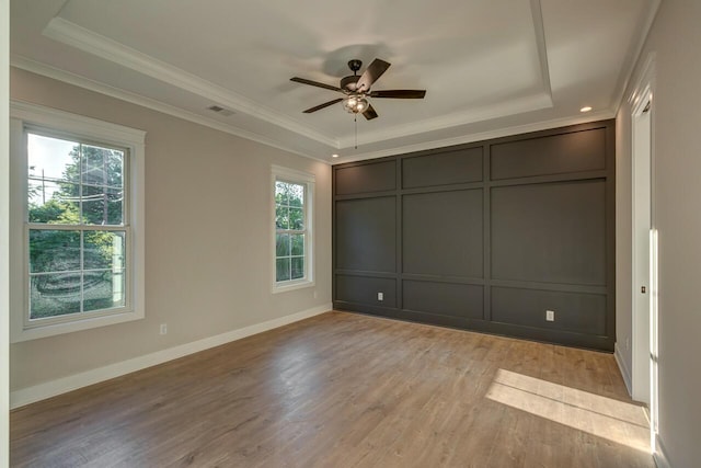 unfurnished bedroom with ceiling fan, crown molding, light hardwood / wood-style flooring, and a raised ceiling