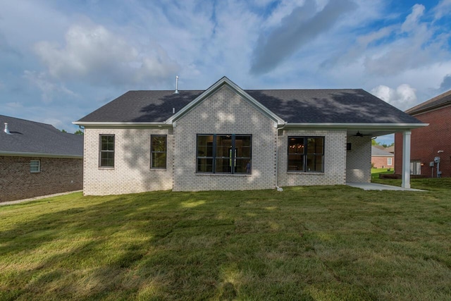 rear view of house with ceiling fan, a patio area, and a lawn