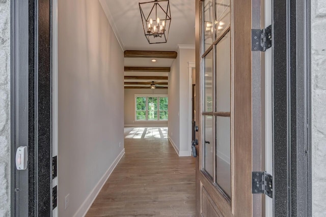 corridor with hardwood / wood-style floors, a notable chandelier, ornamental molding, and beamed ceiling