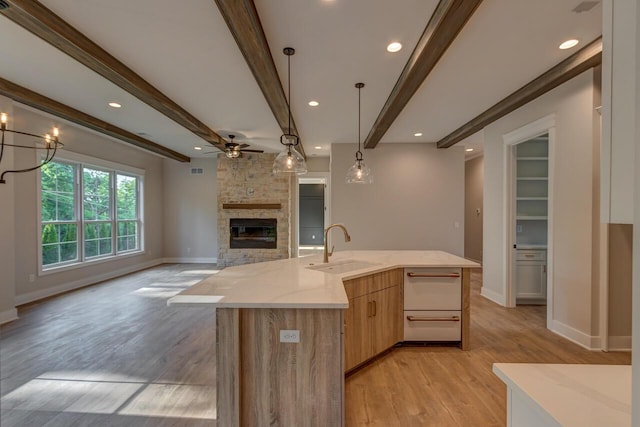 kitchen with sink, hanging light fixtures, light hardwood / wood-style flooring, and beam ceiling