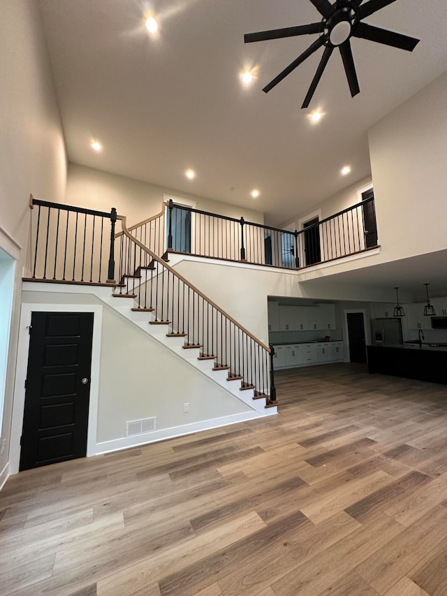 interior space with hardwood / wood-style floors, ceiling fan, and a high ceiling