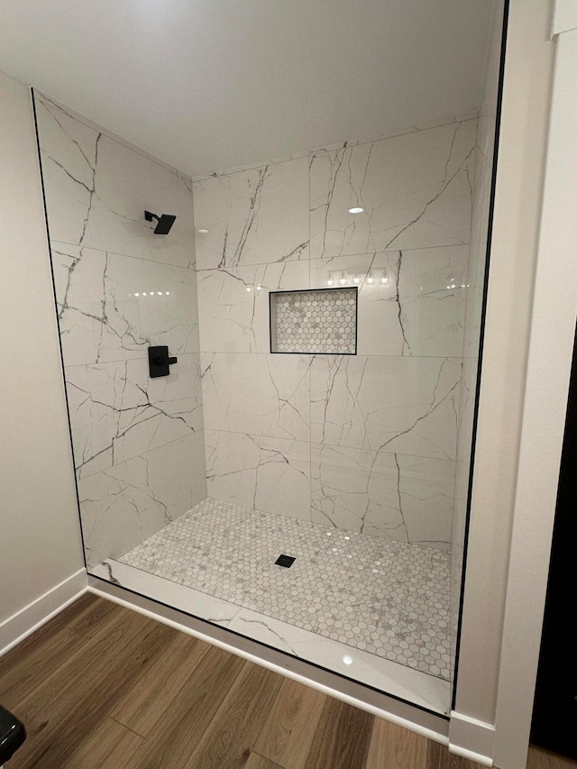 bathroom featuring wood-type flooring and a tile shower