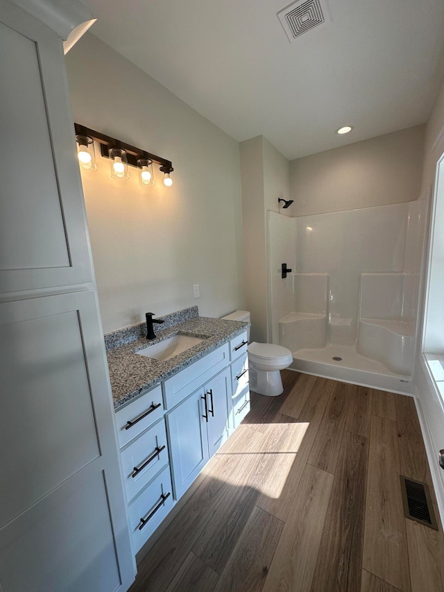 bathroom featuring walk in shower, toilet, vanity, and hardwood / wood-style flooring