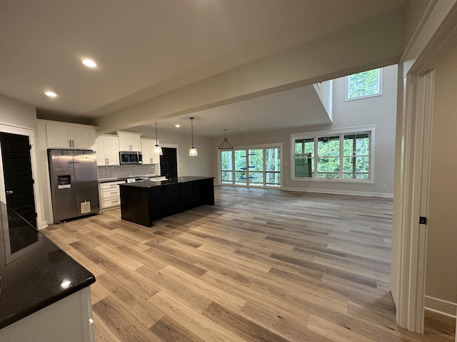 kitchen with pendant lighting, a center island, white cabinets, appliances with stainless steel finishes, and tasteful backsplash