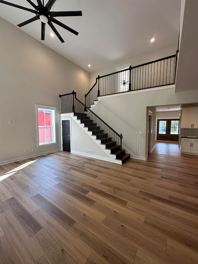 interior space with a high ceiling, hardwood / wood-style flooring, and ceiling fan