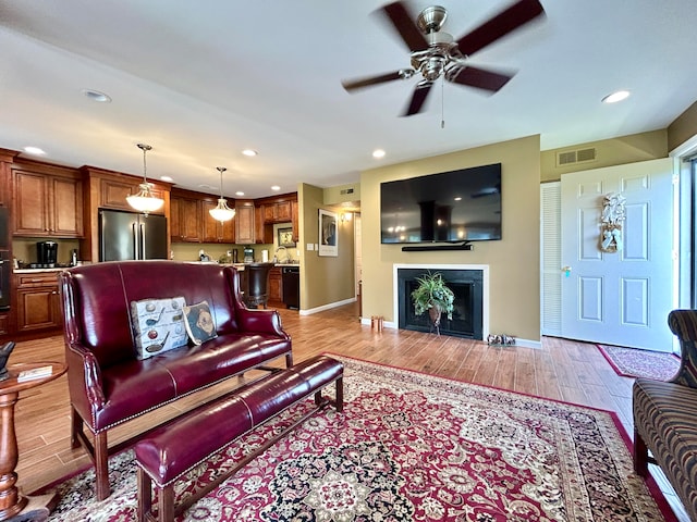 living room with sink, light hardwood / wood-style floors, and ceiling fan