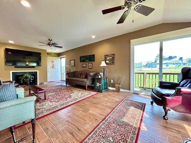 living room with lofted ceiling, ceiling fan, and light wood-type flooring