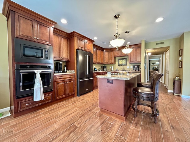 kitchen with a kitchen bar, a kitchen island, light hardwood / wood-style flooring, stainless steel appliances, and pendant lighting