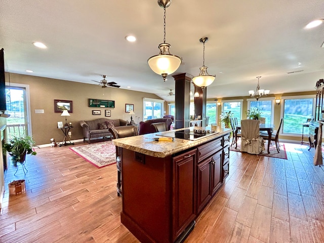 kitchen featuring a center island, black electric stovetop, ceiling fan with notable chandelier, light hardwood / wood-style flooring, and pendant lighting