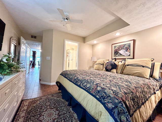 bedroom featuring dark hardwood / wood-style flooring, ceiling fan, and a textured ceiling