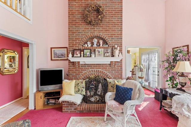 living room featuring brick wall, light carpet, a high ceiling, and a fireplace