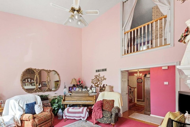 living room with ceiling fan with notable chandelier and a towering ceiling