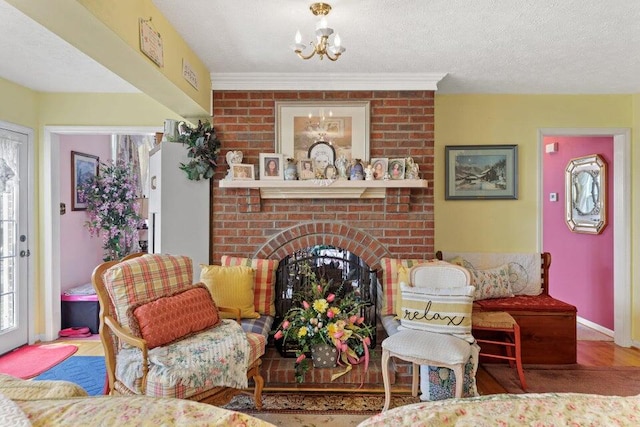 living room with a textured ceiling, hardwood / wood-style floors, a notable chandelier, and a brick fireplace