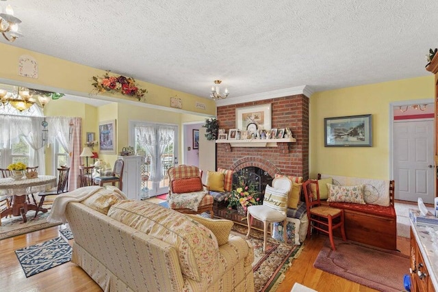 living room featuring brick wall, light hardwood / wood-style flooring, a notable chandelier, and a fireplace