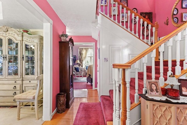 foyer entrance with light hardwood / wood-style flooring and a textured ceiling