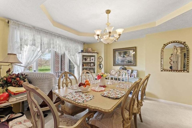 dining area featuring light carpet, a textured ceiling, a tray ceiling, and an inviting chandelier