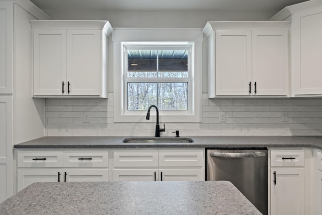 kitchen with dishwasher, tasteful backsplash, white cabinetry, dark stone countertops, and sink