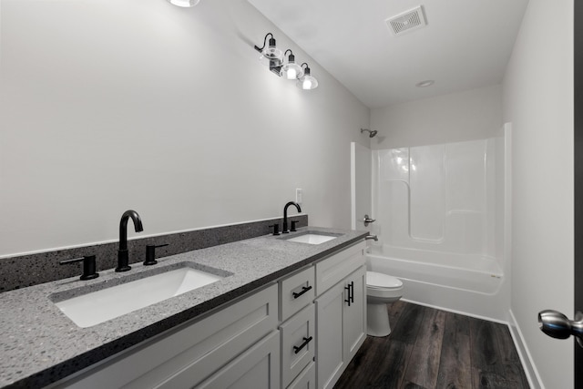 full bathroom with double sink vanity, hardwood / wood-style flooring, toilet, and washtub / shower combination