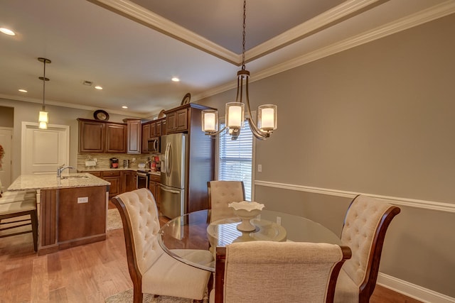 dining room featuring ornamental molding, an inviting chandelier, and light wood-type flooring