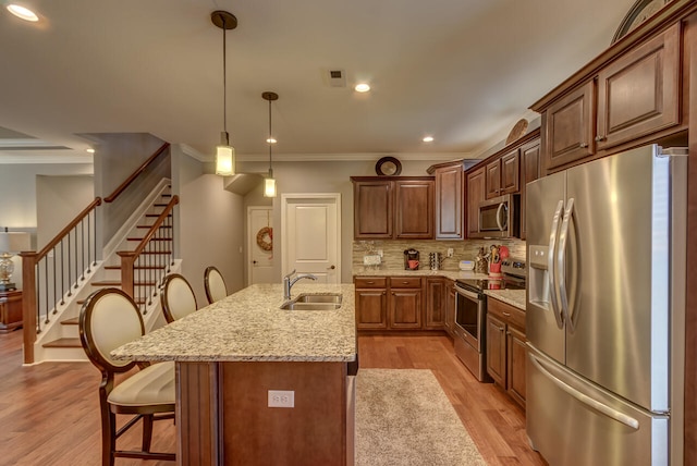 kitchen featuring a kitchen breakfast bar, light hardwood / wood-style flooring, stainless steel appliances, and decorative light fixtures