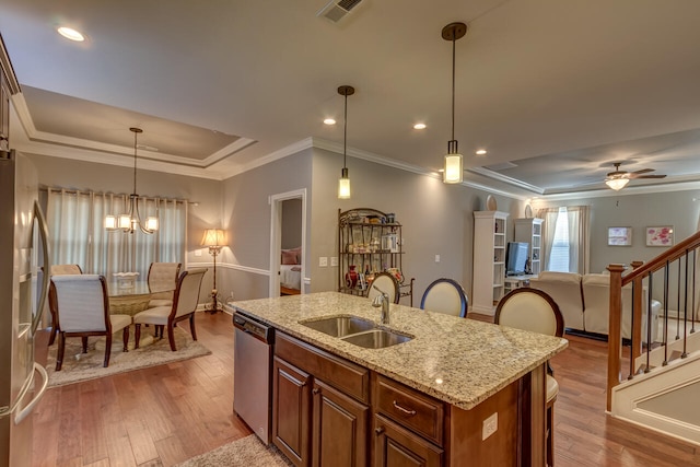 kitchen with appliances with stainless steel finishes, sink, light wood-type flooring, and hanging light fixtures