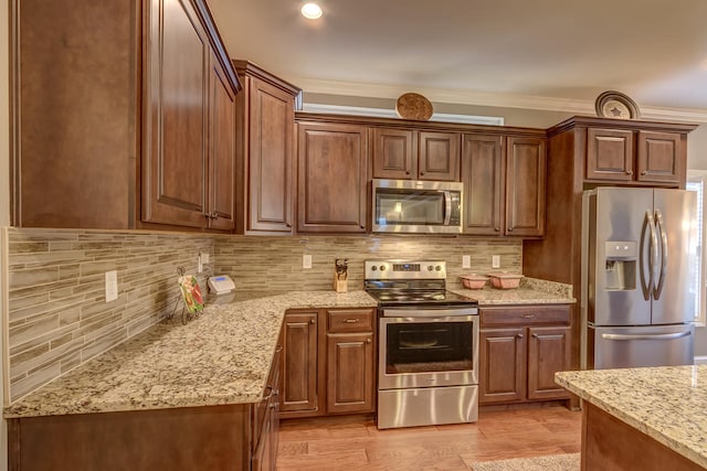 kitchen with backsplash, stainless steel appliances, light stone counters, light wood-type flooring, and ornamental molding