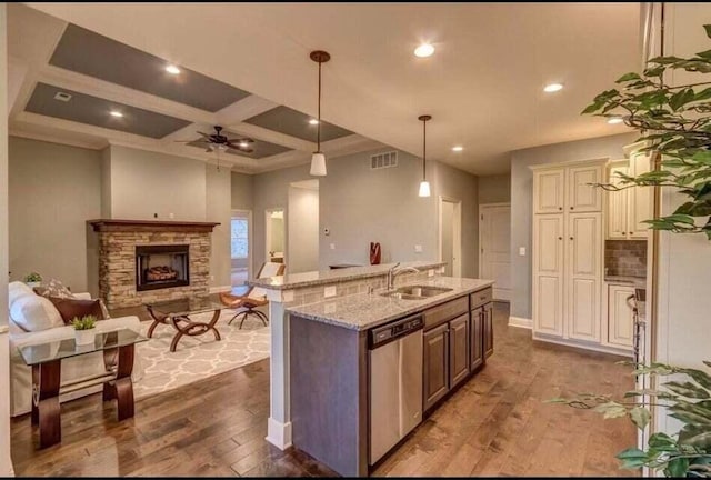 kitchen featuring a stone fireplace, coffered ceiling, dishwasher, dark hardwood / wood-style flooring, and light stone countertops