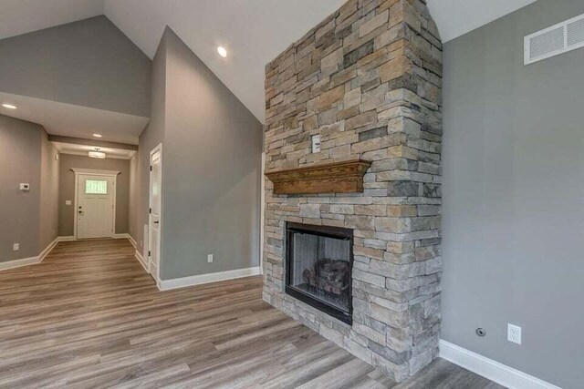 313 Old Station Rd, Frankfort, KY 40601 - unfurnished living room featuring a stone fireplace, baseboards, visible vents, and wood finished floors