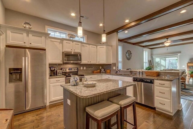 kitchen featuring plenty of natural light, appliances with stainless steel finishes, dark hardwood / wood-style floors, and beamed ceiling