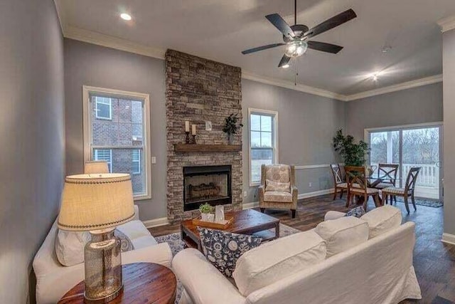 living room featuring ceiling fan, a healthy amount of sunlight, a fireplace, and dark wood-type flooring