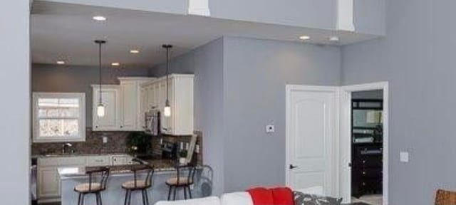 kitchen with hanging light fixtures, a kitchen breakfast bar, backsplash, and range