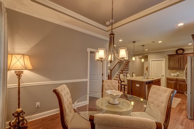 dining space with ornamental molding, sink, a chandelier, and dark hardwood / wood-style floors