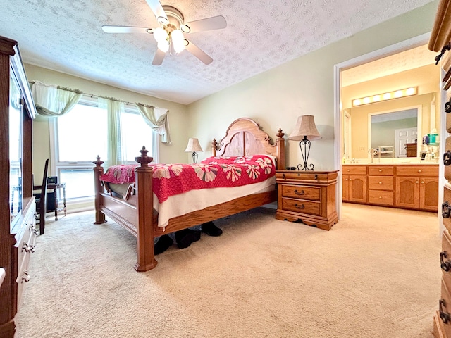 bedroom featuring light colored carpet, connected bathroom, ceiling fan, and a textured ceiling